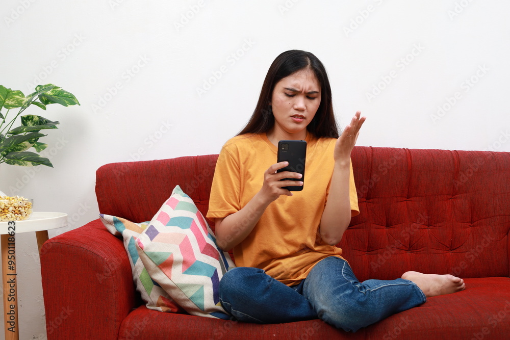 Confused angry asian woman sit on couch at home read spam message on phone screen have problem with correct work. Shocked mad mixed race lady web store client deal with scam online. Copy space Confused angry asian woman sit on couch at home read spam message on phone screen have problem with correct work. Shocked mad mixed race lady web store client deal with scam online. Copy space