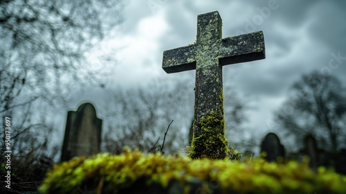 Close-up of a mossy concrete cross seen from a low angle, standing solitary in an old, neglected cemetery under a moody sky.