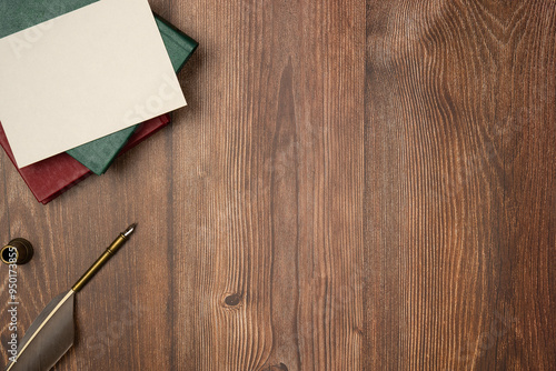 Empty white paper list with quill pen and books on wooden background from above. Vintage style. Space for text. Copy space