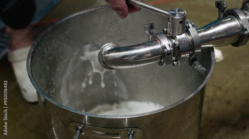 Closeup of stainless steel container being filled with liquid from pipe. Unrecognizable worker operating valve to control filling process Closeup of stainless steel container being filled with liquid from pipe. Unrecognizable worker operating valve to control filling process