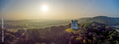 Sunrise castle panorama picture. A landmark image with a golden sunrise over green fields.  photo