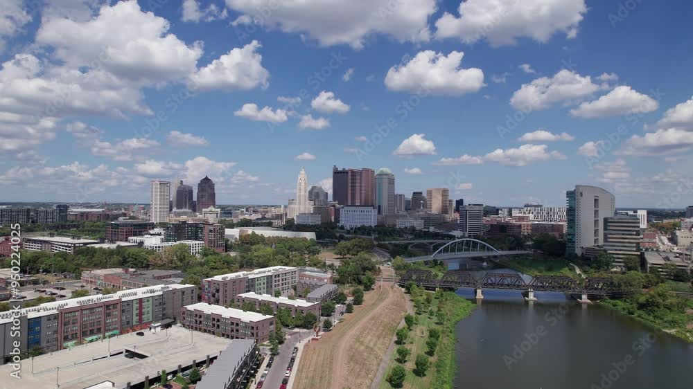 Drone aerial of cityscape, buildings, skyscrapers, and high-rises of capital city of Columbus, Ohio in United States, with new Peninsula and Franklinton construction and homes in the foreground