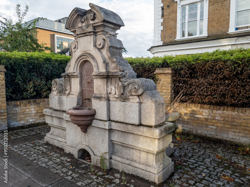 An old, traditional drinking fountain by the side of street.