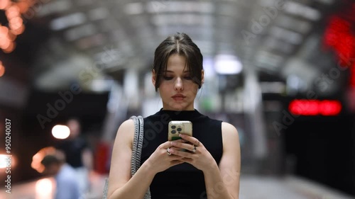 Wallpaper Mural Stylish young woman reading a text message on her mobile phone while waiting for a subway train Torontodigital.ca