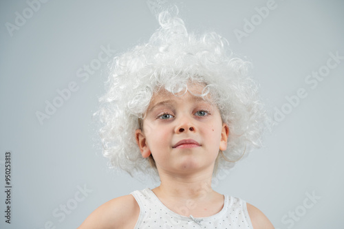 Portrait of a little Caucasian girl wearing a white curly wig on a white background. 