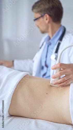 Doctor man is using ultrasound equipment on the back of a patient, woman. The results are on a monitor in the background. Medicine service concept