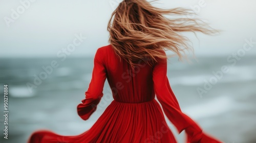 A vibrant image of a woman with windswept hair, dressed in a red gown. She stands facing the vast ocean, her posture radiating vitality and freedom, blending beautifully with nature. photo