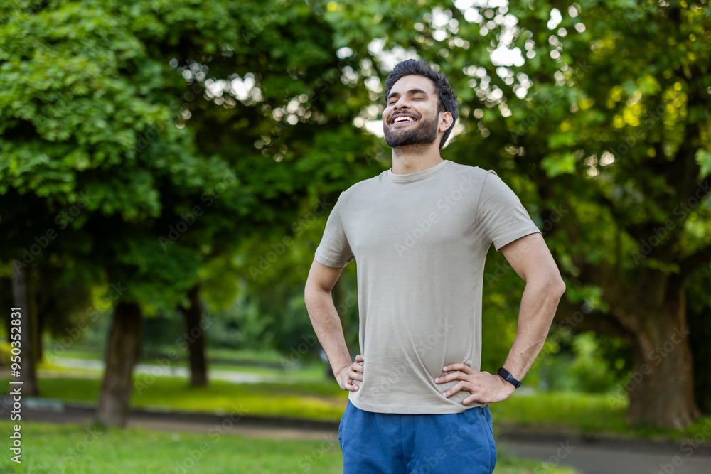 Joyful sportsman relaxing in park after invigorating workout outdoors on sunny day Joyful sportsman relaxing in park after invigorating workout outdoors on sunny day