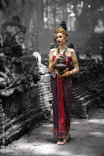 Pretty woman in apsara dvaravati costume standing in ancient temple photo