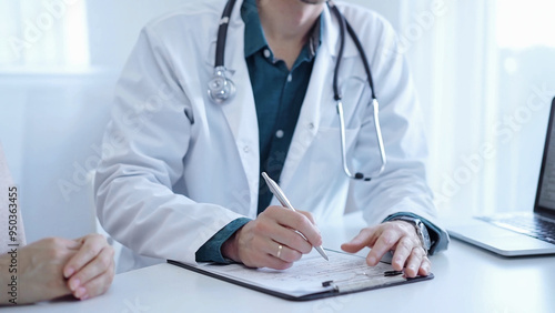 Doctor and a patient. The physician, wearing a white medical coat over a green shirt, is gesturing with his hands during a consultation in the clinic. Medicine