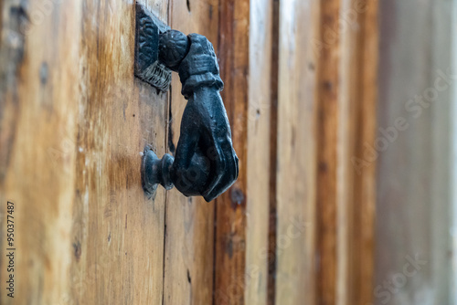 Old metal door handle in the shape of a hand on a wooden doo photo