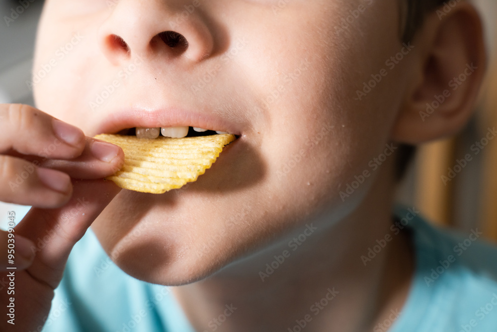 Boy eats potato chip. Focus on the food and face on background Boy eats potato chip. Focus on the food and face on background