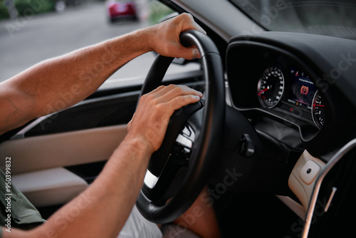 Hands gripping a car steering wheel while driving in a city environment The dashboard displays various indicators