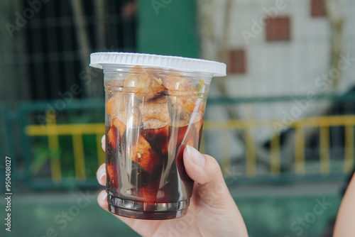 A person is holding a cup of tahu gejrot, traditional food from Indonesia. photo