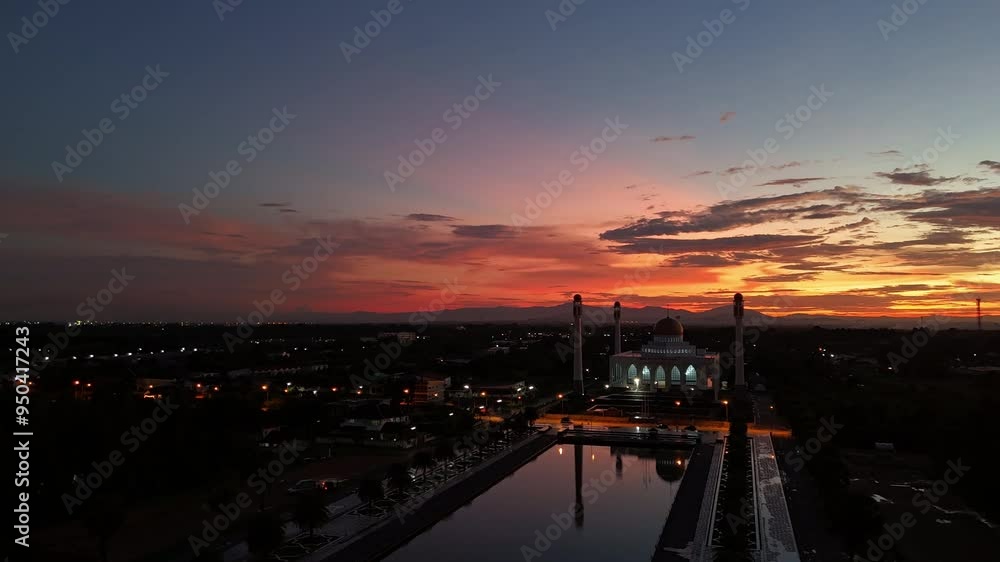 Mosque at Sunset: A breathtaking aerial view of a mosque silhouetted against a vibrant sunset sky, its reflection shimmering in a tranquil pond. The scene evokes a sense of peace and serenity, capturi Mosque at Sunset: A breathtaking aerial view of a mosque silhouetted against a vibrant sunset sky, its reflection shimmering in a tranquil pond. The scene evokes a sense of peace and serenity, capturi