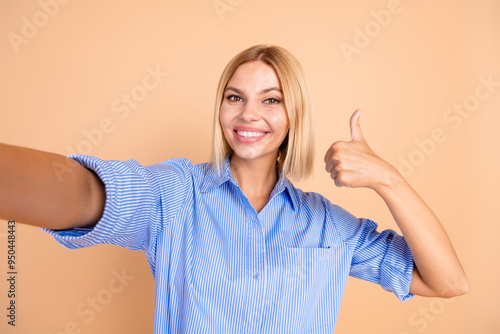 Photo of shiny attractive lady dressed formal shirt showing thumb up tacking selfie isolated beige color background