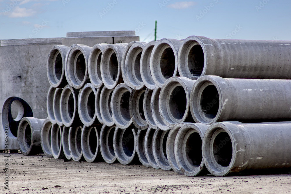 A pile of concrete sewer pipe in a construction site yard A pile of concrete sewer pipe in a construction site yard