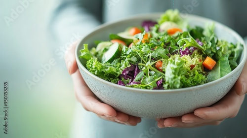 A person holding a bowl of vibrant mixed green salad, filled with a variety of fresh vegetables, representing a healthy, nutritious, and balanced dietary choice. photo