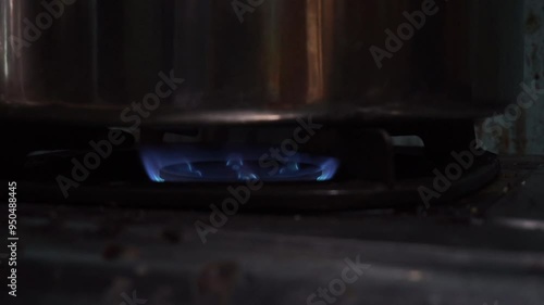 Close-up of a blue gas flame burning under a pot.