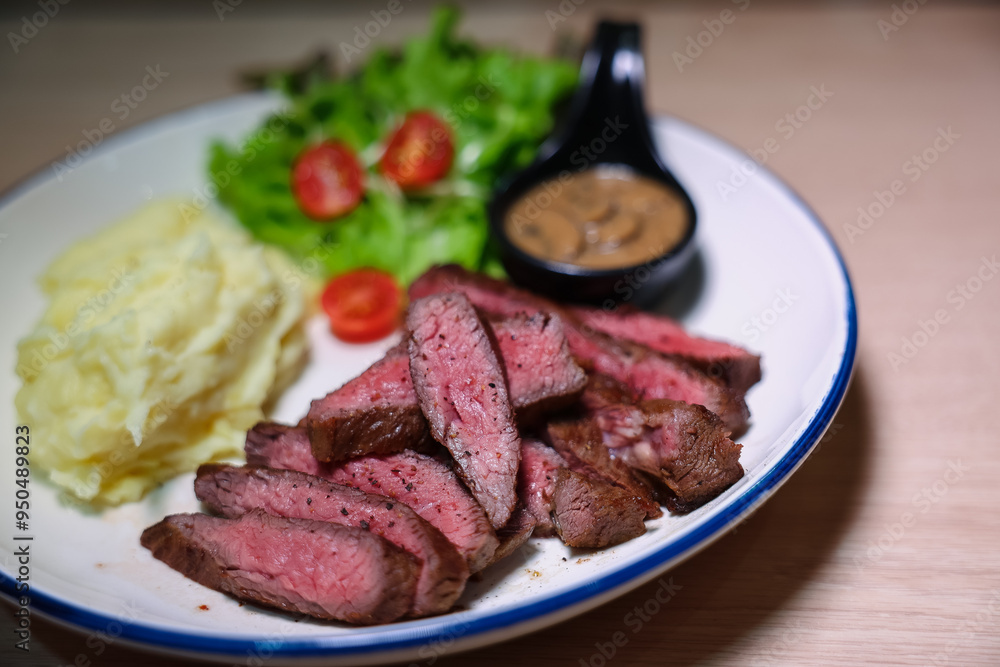 Medium rare steak, cut into bite-sized pieces, served with pepper sauce, mashed potatoes and salad. Medium rare steak, cut into bite-sized pieces, served with pepper sauce, mashed potatoes and salad.