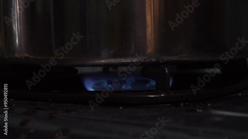Close-up of a gas stove burner with a pot on top.