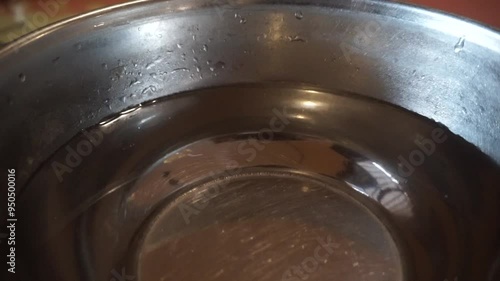 Close-up of a stainless steel bowl with water droplets.
