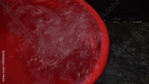 Closeup of red basin being filled with water.