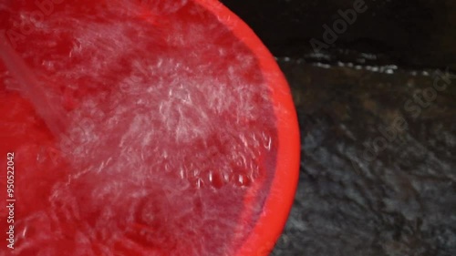 Closeup of water swirling in a red bucket.