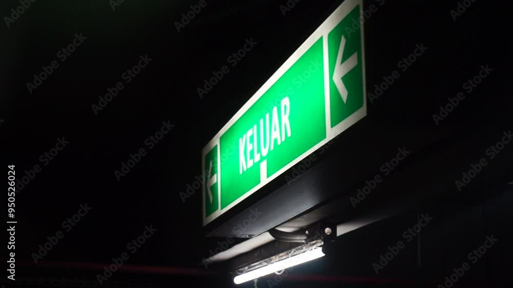 Green exit sign with an arrow pointing left in a dark environment. Green exit sign with an arrow pointing left in a dark environment.