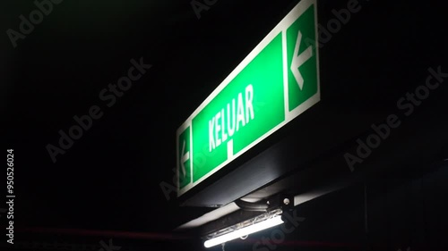 Green exit sign with an arrow pointing left in a dark environment.