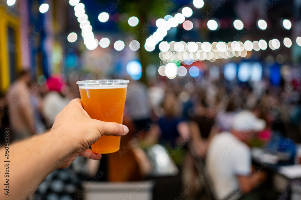 Hand holding a plastic cup of beer with a blurred festival background. Bokeh lights create a lively atmosphere, capturing the essence of a fun outdoor event. Perfect for themes of celebration Hand holding a plastic cup of beer with a blurred festival background. Bokeh lights create a lively atmosphere, capturing the essence of a fun outdoor event. Perfect for themes of celebration