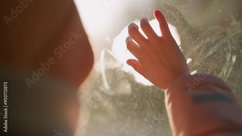 Wallpaper Mural A creative moment as a little girl in a pink cap, jacket, and white winter scarf sits in a car, cleaning and writing on the fogged window glass Torontodigital.ca