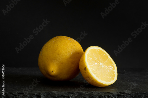 yellow Lemon and lemon half on black surface and black background