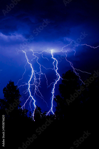 beautiful lightning during a thunderstorm at night in a forest that caused a fire, against a dark sky with rain