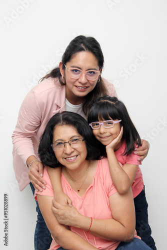 Three generations of brunette Latina women, grandmother, mom and daughter with glasses show their love and family support celebrate Mother's Day