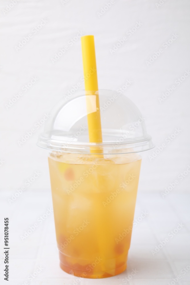 Fototapeta premium Tasty bubble tea in plastic cup on white tiled table against light background