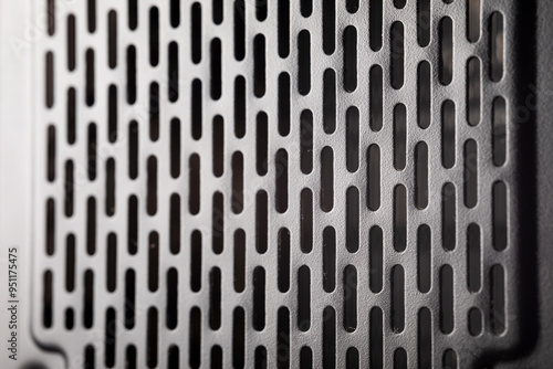 Close-up of metal vent grill with rectangular holes. Industrial design element.