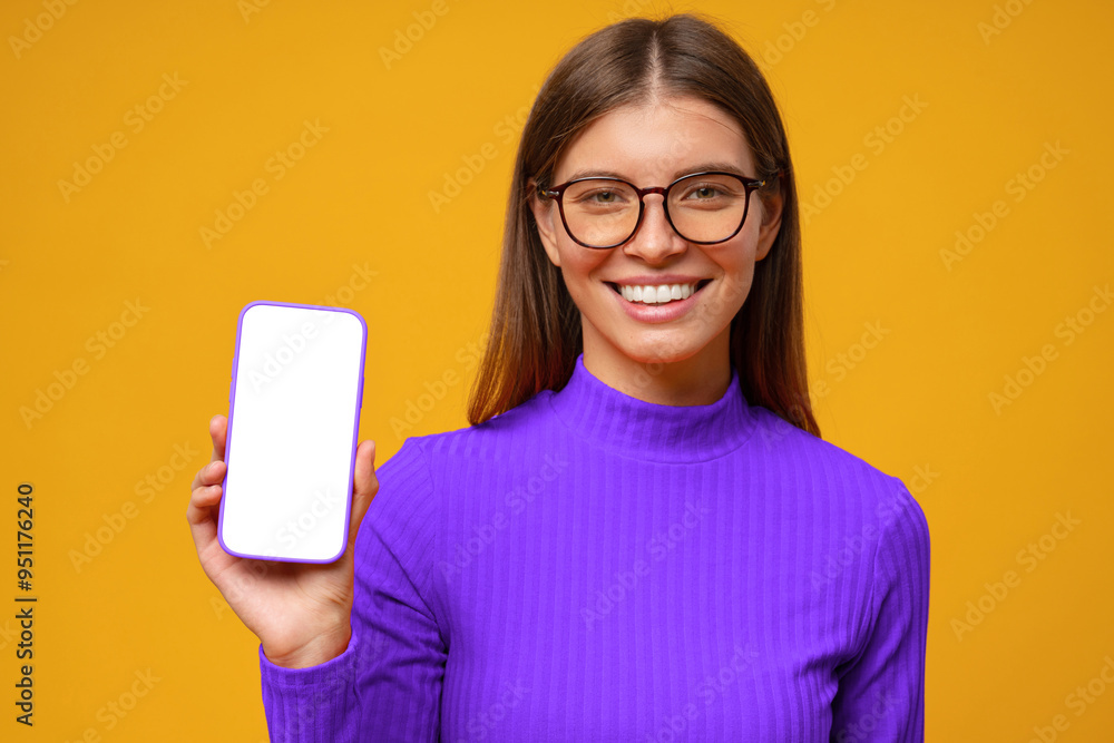 Portrait of smiling happy young woman holding blank phone screen, isolated on yellow background Portrait of smiling happy young woman holding blank phone screen, isolated on yellow background