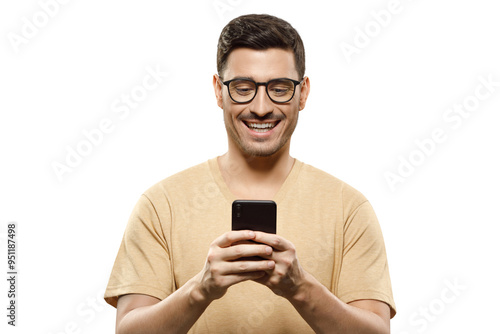 Portrait of young handsome man in beige t-shirt and glasses, laughing at content he sees on phone screen