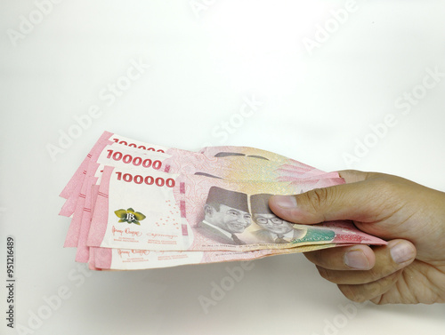 A man's hand is holding one hundred thousand Indonesian banknotes. Cash payment concept. Indonesian rupiah currency (Rp. 100,000 One Hundred Rupiah) on a white background