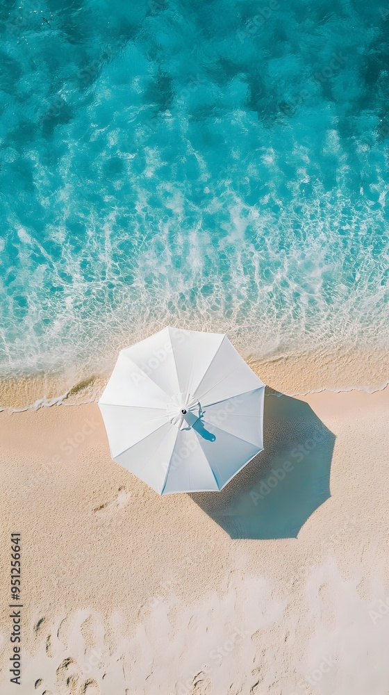 Naklejka premium Aerial View of a Lone Beach Umbrella in a Tranquil Summer Paradise