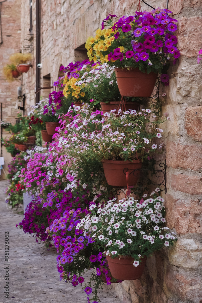 Naklejka premium Pots of plants hanging on the side of a brick wall.