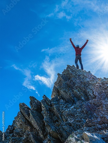 A tenacious climber revels in victory atop a rugged peak, symbolizing perseverance and aspiration against a backdrop of endless blue.