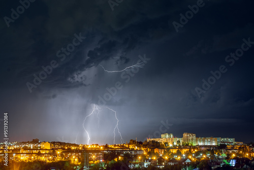 Lightning strikes in the night city among the menacing black clouds. Storm and thunderstorm