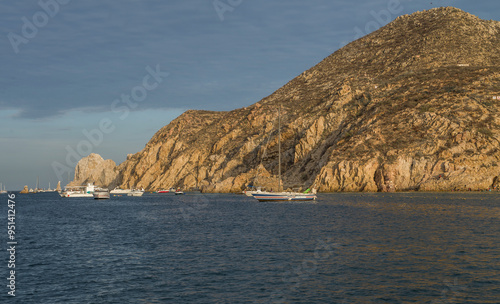 ourist boats or yachts sailing around the arch of Cabo San Lucas during the summer holidays in Mexico. Baja style sunset photo