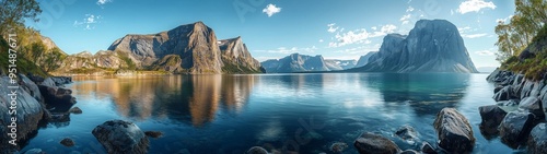 Panoramic view of a serene fjord surrounded by rugged mountains under a bright, clear sky, reflecting in calm waters.