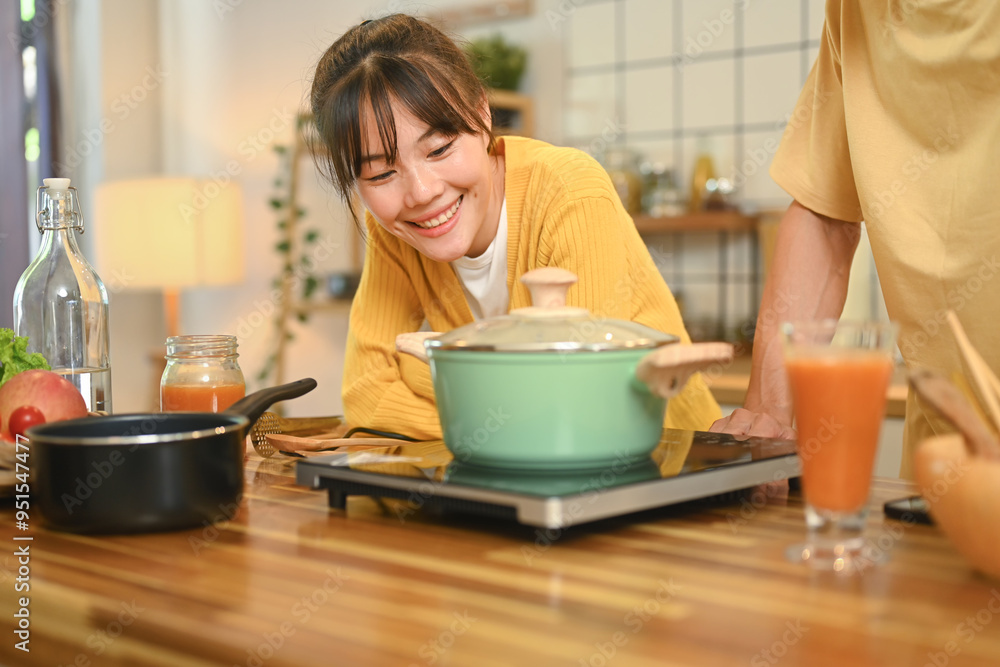 Pretty young woman enjoying cooking time with her husband in a cozy kitchen Pretty young woman enjoying cooking time with her husband in a cozy kitchen