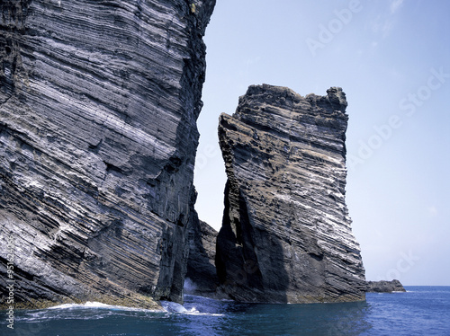 Jeju-si, Jeju-do, South Korea - July 15, 2006: Summer view of beautiful sedmentary rock cliff on the sea at Udo Island with the background of sea horizon photo