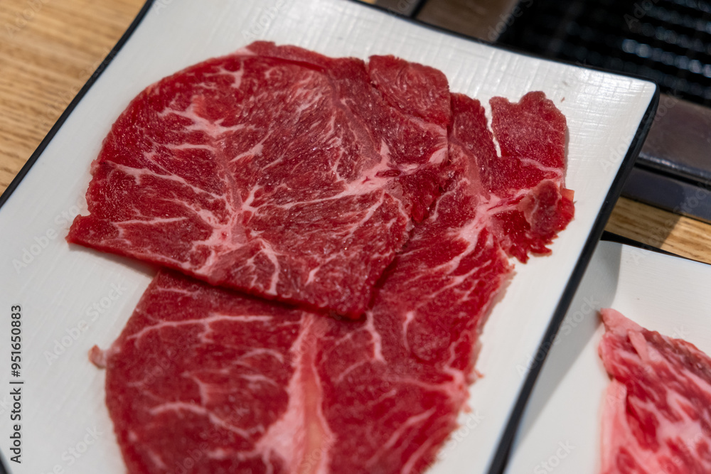 Obraz premium Korean Style Barbecue on plate in front of stainless grill. BBQ rare meat with soft focus