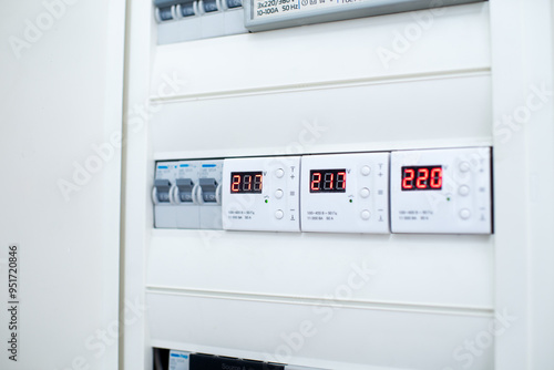 Close-up of a modern electrical control panel with digital voltage displays and circuit breakers. photo